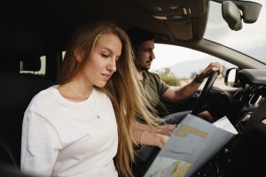 A young couple on a road trip, with the girl looking at a paper map.