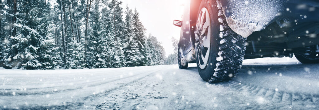 Close-up of snow-covered winter tires driving on an icy road.