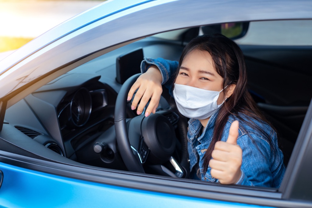 A woman wearing a medical facemask in her car during the COVID-19 pandemic.