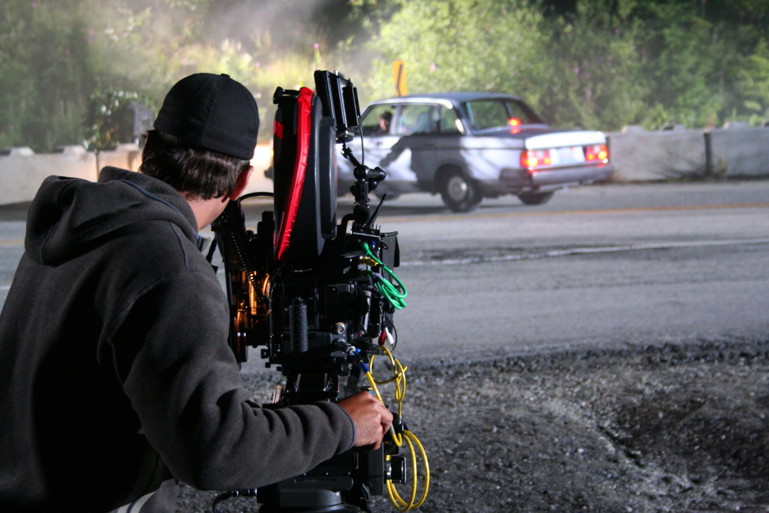 A cameraman films staged movies cars crashes on set during a TV miniseries production.