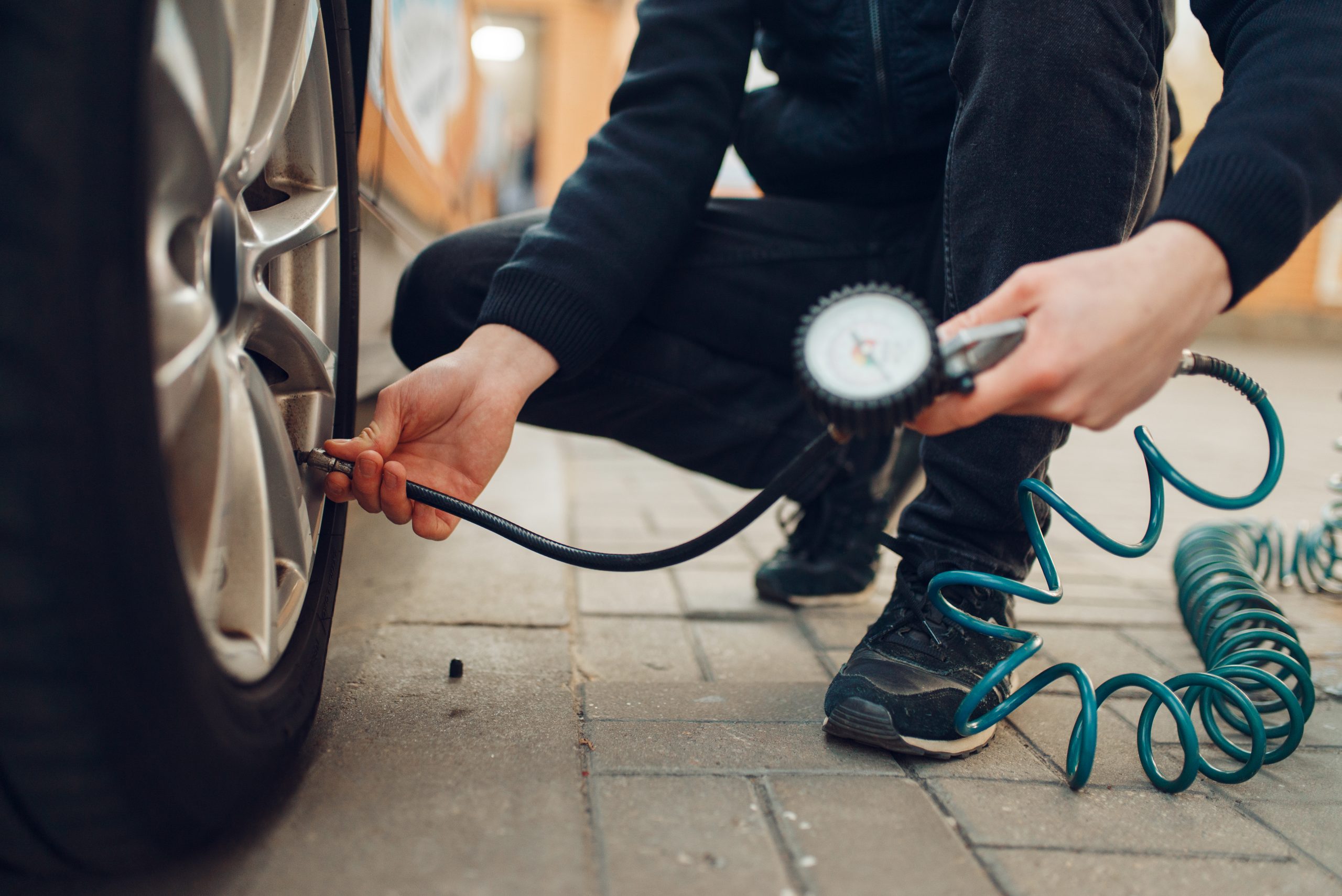 man-checking-tire-pressure-car-maintenance A man checking the tire pressure of a tire on his car.