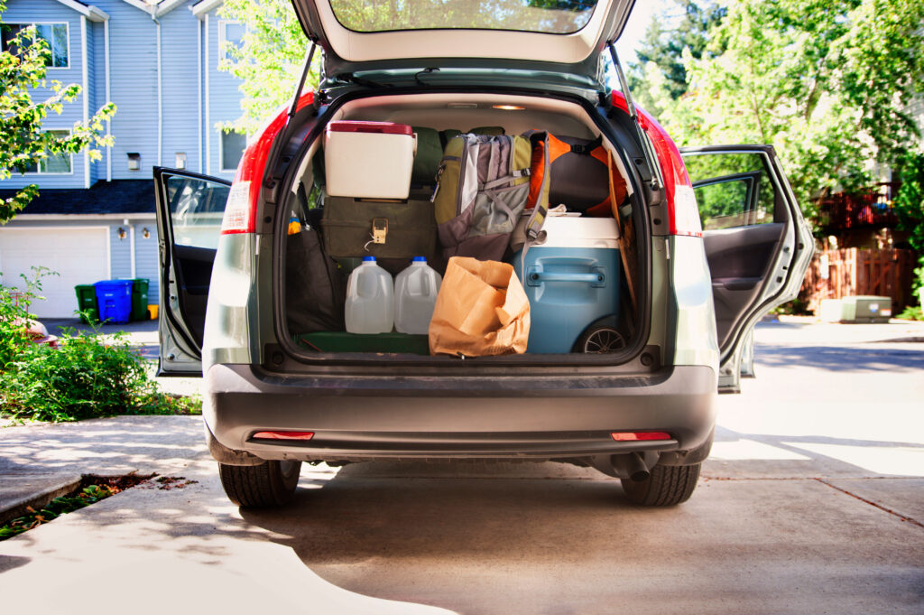 A car trunk packed with essential tailgate supplies, including coolers, bags, and water jugs, ready for a game day event.
