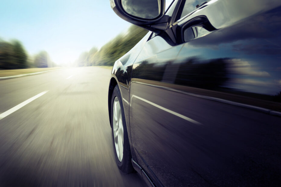 A sleek black car drives quickly down an open road, symbolizing financial momentum and modern leasing flexibility.