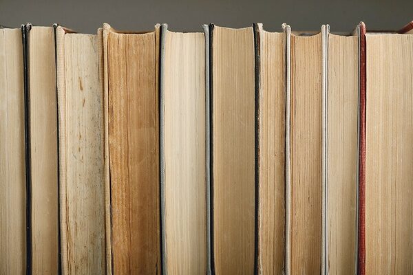 Stack of vintage hardcover books with aged pages on a library shelf