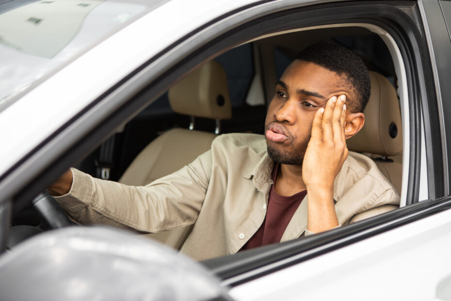 Young man looking frustrated while sitting in his car